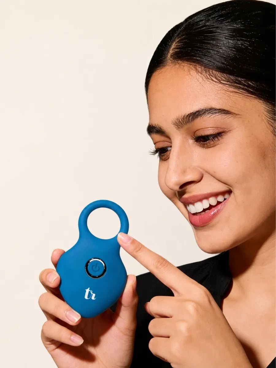 A customer smiling as she holds a blue Thrillerrr ring massager