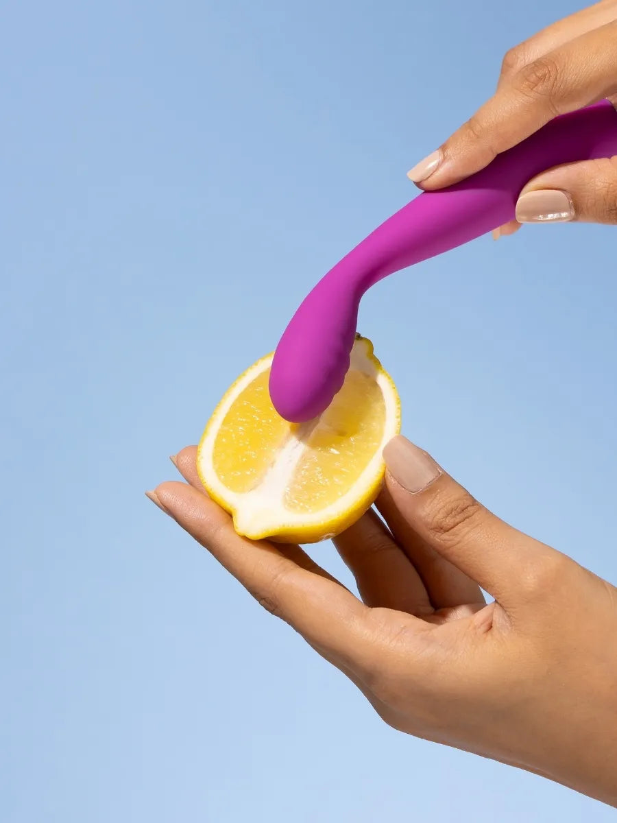 Magenta silicone wand flexing against a lemon half to show how soft it is