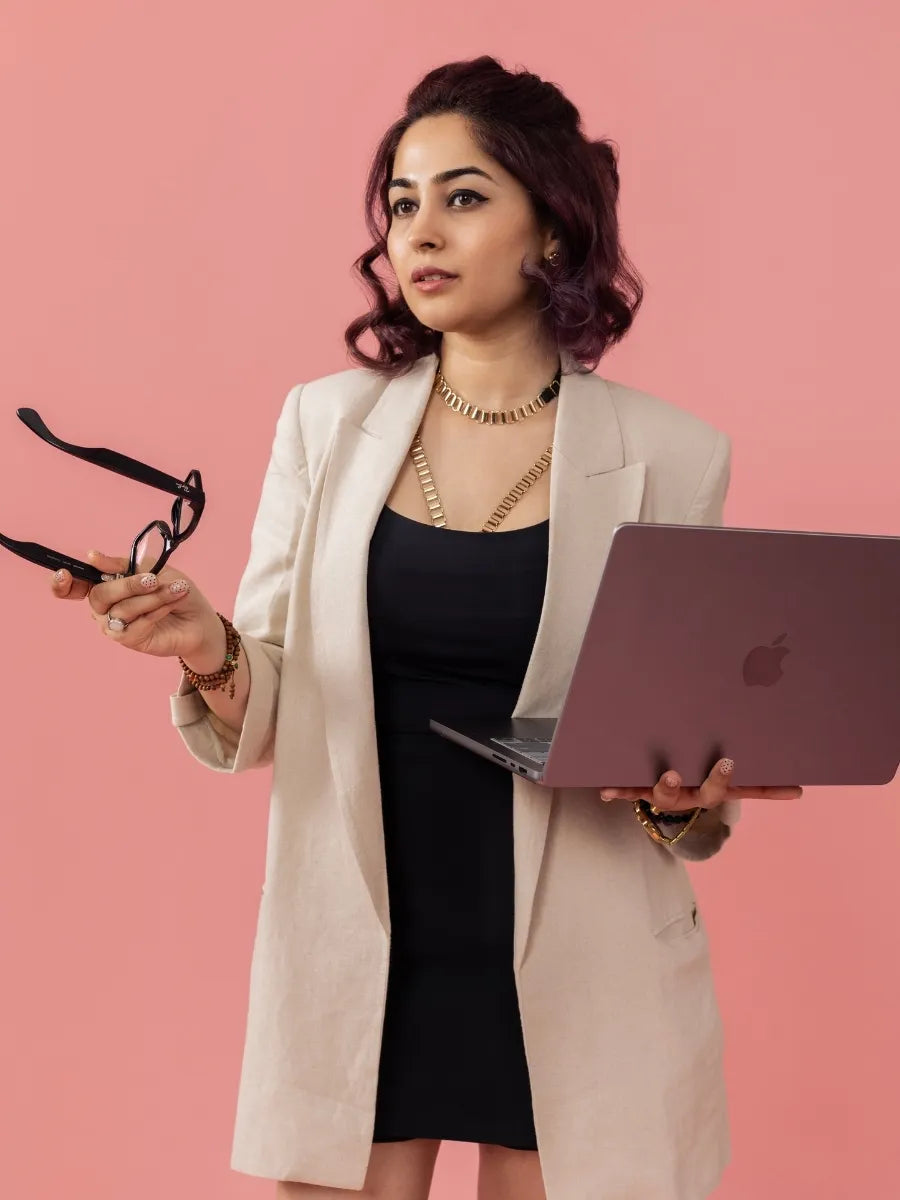 Arisha Nigam, founder of Thrillerrr, holding a laptop against a pink backdrop